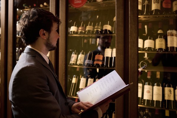 Kuno, cadre junior stagiaire, compare le stock des 250 vins - tous européens - avec la carte.
