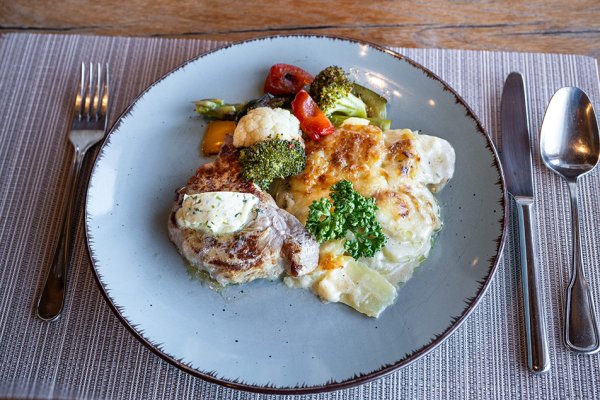 Das Mittagsmenu: Steak vom Kräuterschwein mit Kräuterbutter, Kartoffelgratin und Marktgemüse