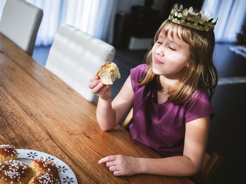 Mädchen isst Dreikönigskuchen und hat eine Krone auf.jpg